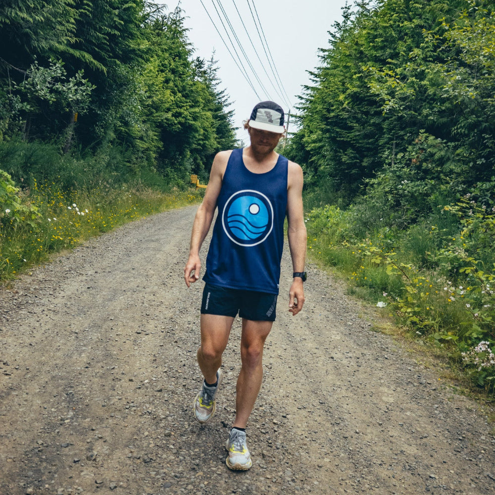 Man walking on a dirt road surrounded by trees and power lines