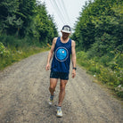 Man walking on a dirt road surrounded by trees and power lines