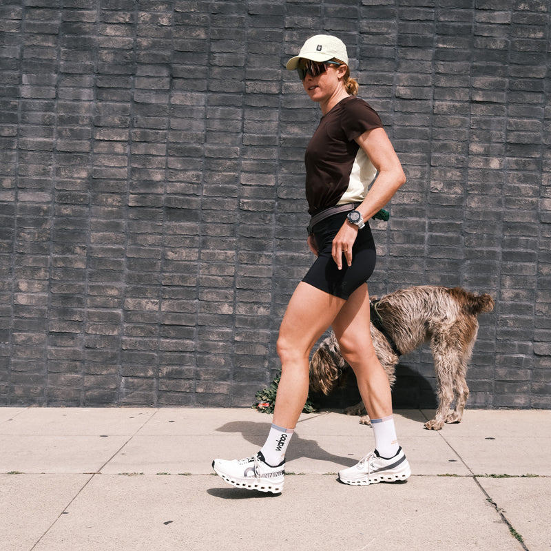 Person walking a dog while wearing On Cloudmonster shoes in a casual outdoor setting.