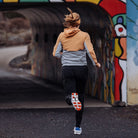 A runner wearing On Cloudmonster shoes, captured from behind while running through an urban tunnel